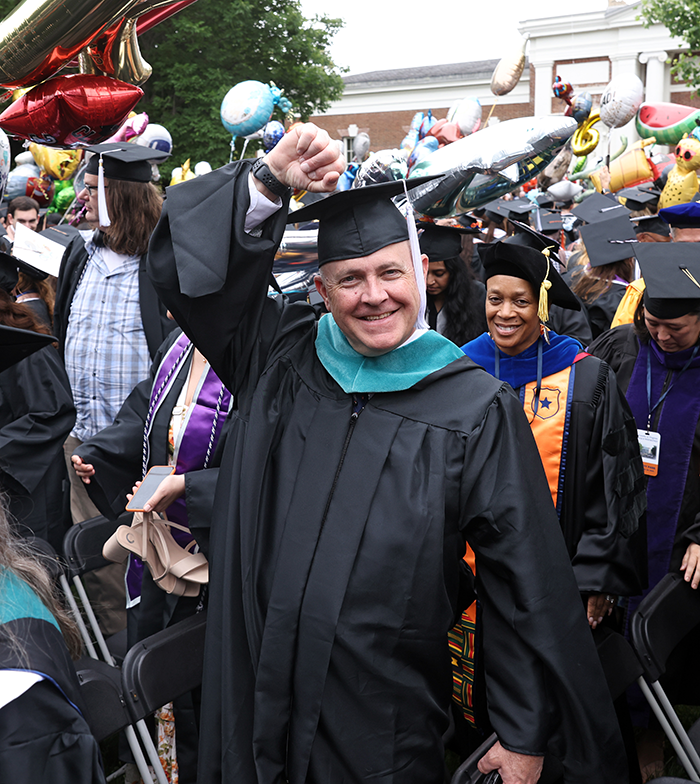 Christopher Easton raising his hand in celebration while walking the lawn during graduation